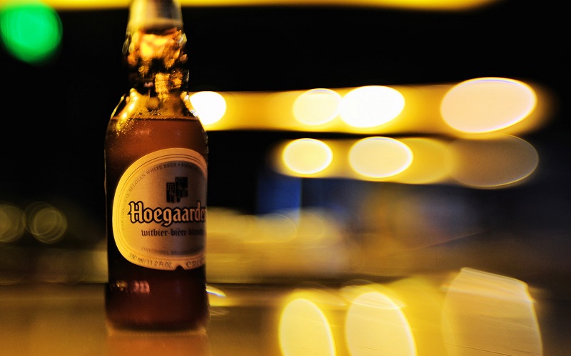 Birra bianca: bottiglia di Hoegaarden su sfondo con gioco di luci - Enjoy Food & Wine